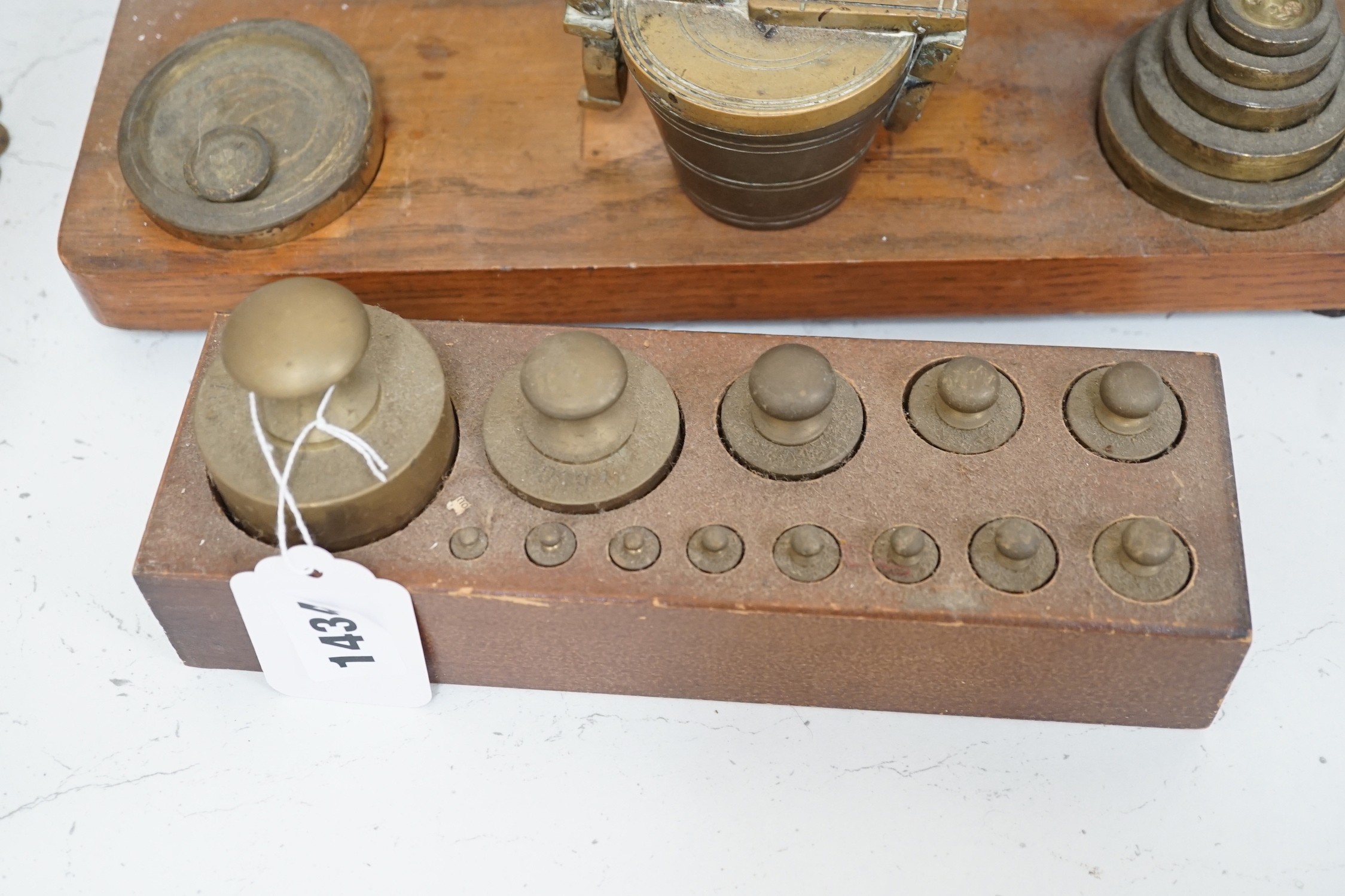 A set of brass postal scales and weights, a separate set of weights and another, set in wooden stand